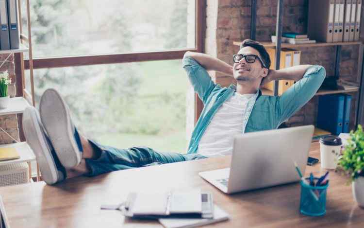 Happy calm smiling man having a rest after solving all the tasks at work